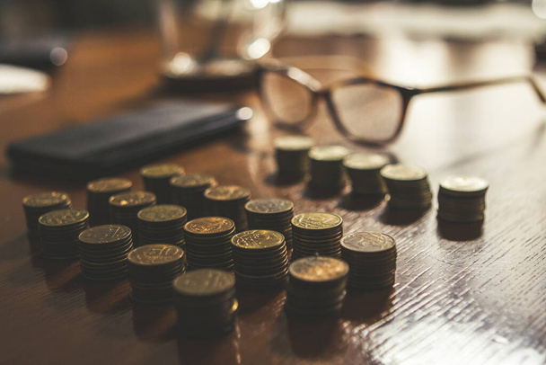 Fila de moedas e óculos em cima de uma mesa, conceito de pobreza - Foto, Imagem