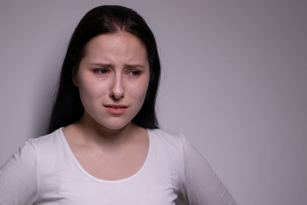  portret van trieste en depressieve jonge vrouw. op grijze achtergrond. zenuwachtig en boos mensen concept - Foto, afbeelding