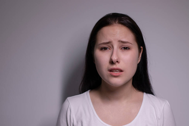  retrato de una joven triste y deprimida. sobre fondo gris. concepto de personas nerviosas y alteradas - Foto, Imagen