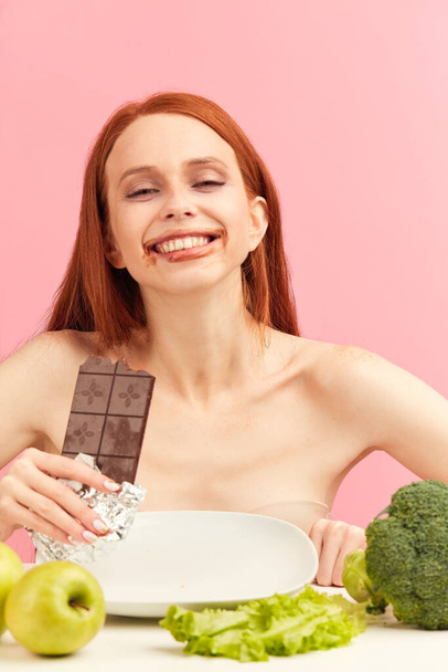 Anorexi woman feels happy while eating chocolate instead of healthy vegetables. - 写真・画像