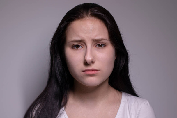  retrato de una joven triste y deprimida. sobre fondo gris. concepto de personas nerviosas y alteradas - Foto, imagen