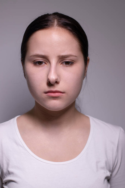  πορτρέτο της θλιμμένης και καταθλιπτικής νεαρής γυναίκας. σε γκρι φόντο. νευρικό και αναστατωμένος άνθρωποι έννοια - Φωτογραφία, εικόνα