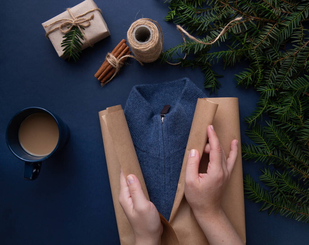  Hands wrapping gift wrapping on blue sweater background - 写真・画像