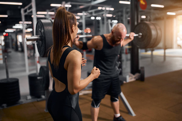 Brutal man with beutiful trainer in gym - Photo, image