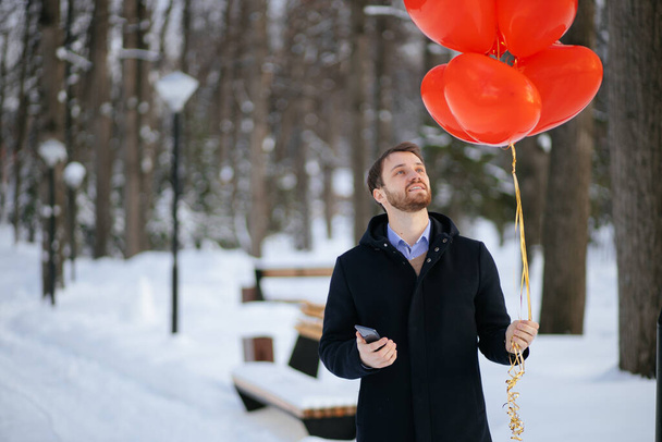 bearded romantic man with red air ballons at winter park - Фото, изображение