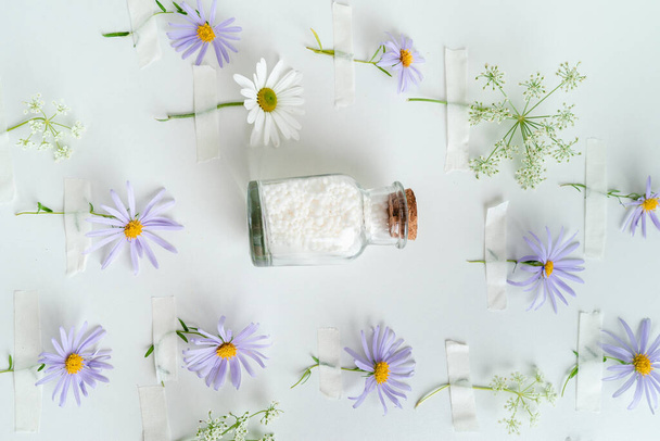 Alternative medicine herbs and homeopathic globules on white background. Homeopathy medicine concept. Bottles of homeopathic beads and medicinal herbs and flowers.  - Fotoğraf, Görsel
