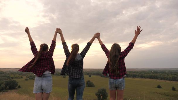 zdravé dívky, ženy jdou na vrchol kopce při západu slunce, zvednou ruce do vzduchu, šťastné a opojené životem, mládím a štěstím. koncept svobody dobrodružství, cestovního ruchu a cestování - Fotografie, Obrázek