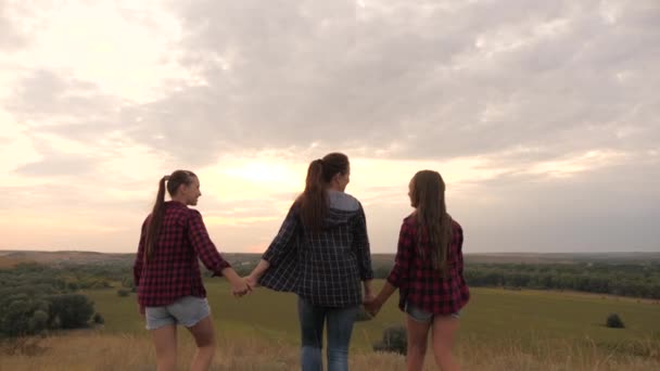 Gesunde Mädchen, Frauen gehen bei Sonnenuntergang auf den Gipfel des Hügels, heben die Hände in die Luft, glücklich und berauscht vom Leben, der Jugend und dem Glück. Konzept der Abenteuer-, Tourismus- und Reisefreiheit - Filmmaterial, Video