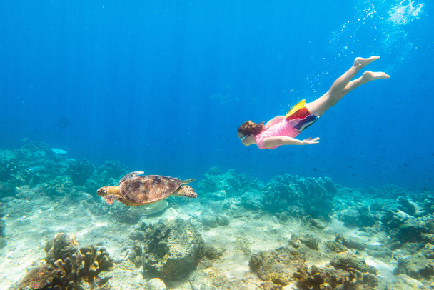 ウミガメと子供のシュノーケリング。子供たちは水中で泳ぐ。子供とビーチ夏休み。サンゴの魚を見ている少女。エキゾチックな島の海洋生物。シュノーケリングとマスクでの子供ダイビング. - 写真・画像