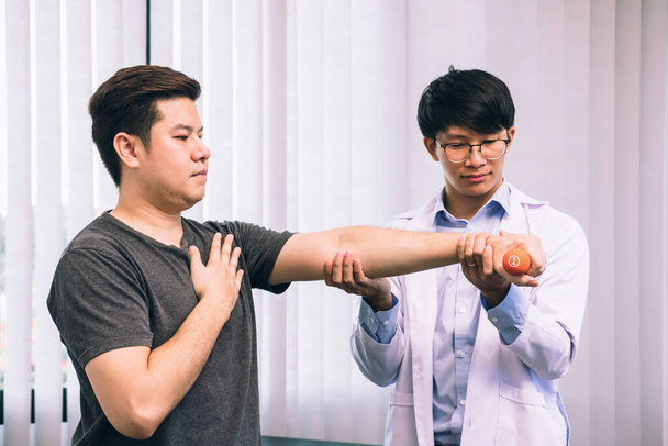 Asiatique jeune homme physiothérapeute aider patient avec levage haltères exercices en clinique. - Photo, image