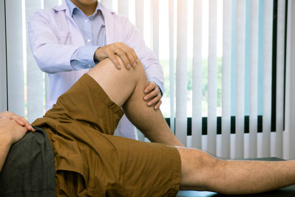 Fizjoterapeuci używają uchwytu do kolana pacjenta, aby sprawdzić ból.. - Zdjęcie, obraz