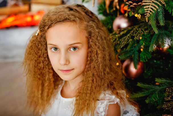 新年とクリスマスの概念。クリスマスの火事できれいな女の子の肖像画。クリスマスの夜、小さな女の子がサンタクロースを待っています。クリスマスの夢を見る女の子. - 写真・画像