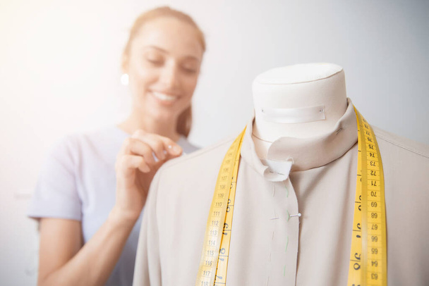 Seamstress σχεδιαστής μόδας νεαρή γυναίκα εργάζεται με μανεκέν, καρφίτσες ράφτη με ύφασμα για φόρεμα - Φωτογραφία, εικόνα