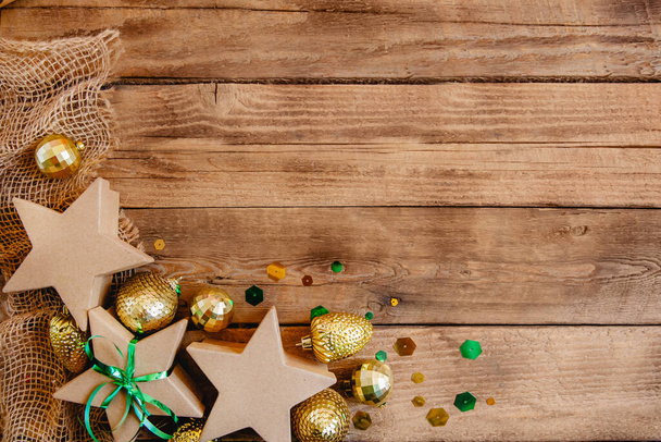 Craft gift boxes in the star shape and Christmas balls on a wooden background. New Year Flat lay with space for text. High quality photo - Φωτογραφία, εικόνα