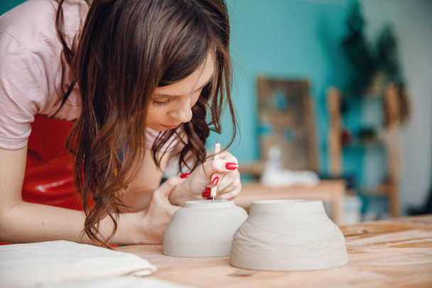 Belle fille potier fait de la poterie pour rôtir au four. Concept artiste artisanat, concentration sur le lieu de travail - Photo, image