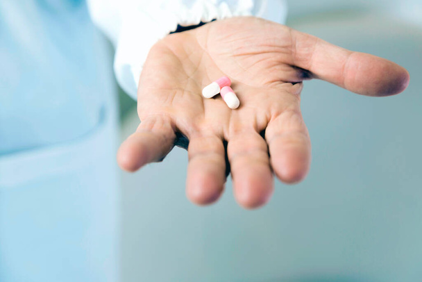 Dokter met witte en roze pillen in zijn hand - Foto, afbeelding