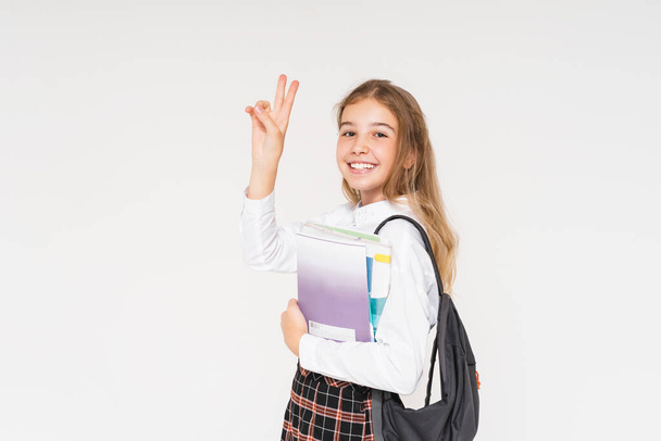 Aranyos mosolygós tini lány iskolai egyenruhában könyvek a kezében elszigetelt fehér háttér - Fotó, kép
