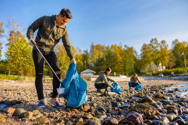 Man cleaning beach with volunteers on sunny day - Photo, Image