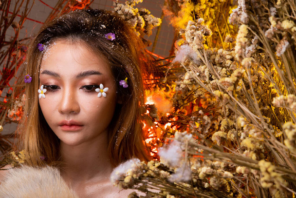 Mooie romantische jonge Aziatische vrouw in Fox staart in struik verscheidenheid van bloemen poseren op de achtergrond fris en gedroogd flora. Inspiratie van de herfst winter sneeuw Parfum, cosmetica concept. - Foto, afbeelding