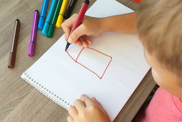 Ein kleines Kind zeichnet ein Haus mit Filzstiften im Album. Schritt für Schritt-Anleitung. - Foto, Bild