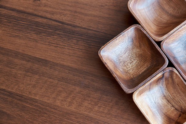 Utensilios de madera para la cocina, cuencos, platos en una mesa de madera. El concepto de platos naturales, un estilo de vida saludable. Textura de madera. Ecología de madera. ensaladera en el fondo de la mesa de madera marrón - Foto, imagen