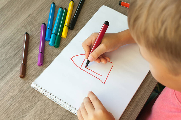 A small child draws a house with markers in the album. Step-by-step instructions. - Фото, зображення