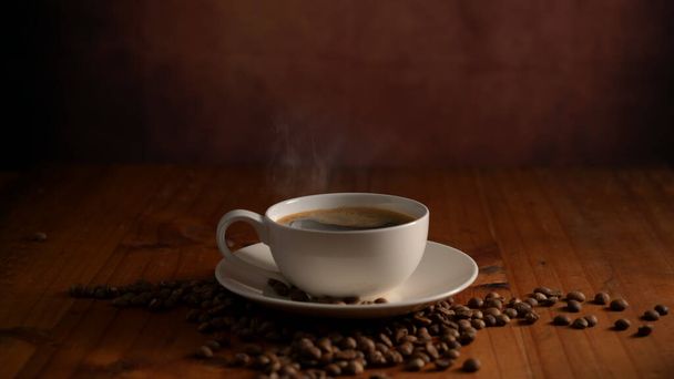 Tahta masaya süslenmiş kahve çekirdekli bir fincan sıcak kahvenin yakın görüntüsü. - Fotoğraf, Görsel
