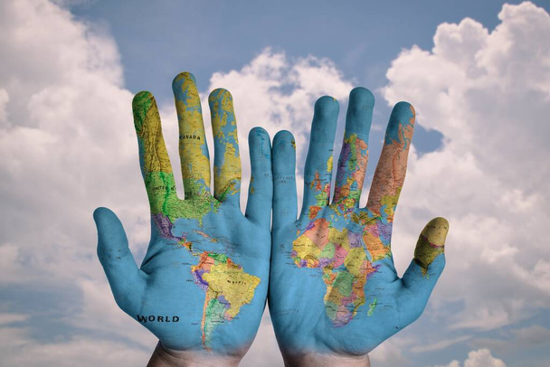 Ο παγκόσμιος χάρτης είναι ζωγραφισμένος και στα δύο χέρια ενός άντρα. - Φωτογραφία, εικόνα
