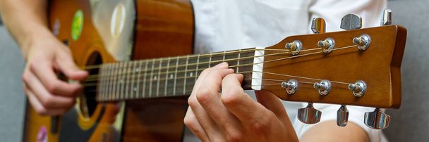 Young boy playing guitar. Close-up of man hand playing classic guitar. teenager learning playing guitar. Banner or panoramic shot. - Photo, Image