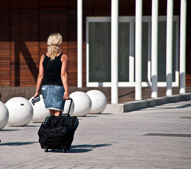 Egy nő egy bőröndöt húz maga mögé. Koncentrálj balra.. - Fotó, kép