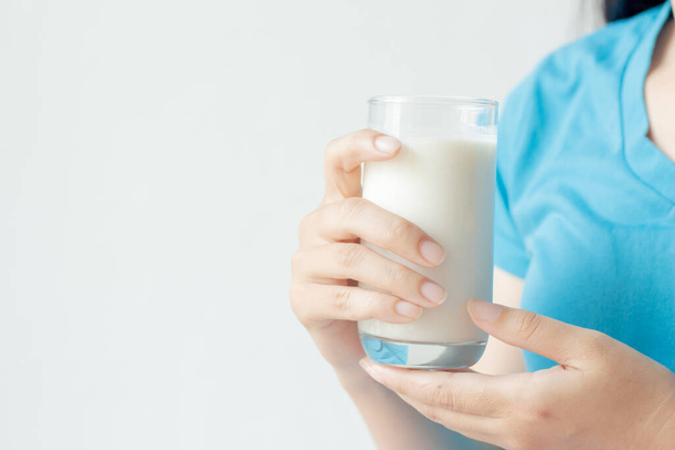 Mujer mano sosteniendo vaso de leche fresca sobre fondo blanco. - Foto, imagen