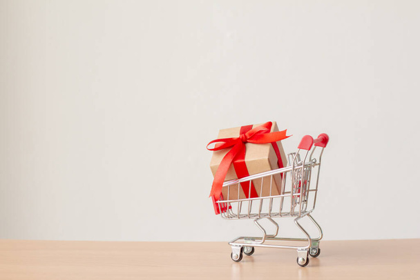 Gift box with red ribbon on shopping cart with copy space. - Φωτογραφία, εικόνα