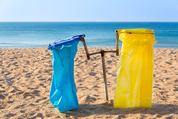 Пустые мешки для мусора на песчаном португальском пляже с синим морем - Фото, изображение