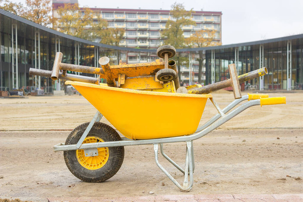 Yellow wheelbarrow with stone cutter on new square pavement - Foto, Imagen