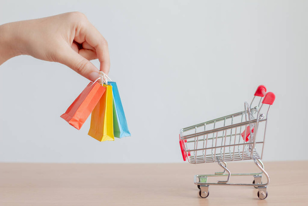 Woman hands holding small shopping bag with shopping cart on table.Online shopping concept.E-commerce. - Foto, Imagem
