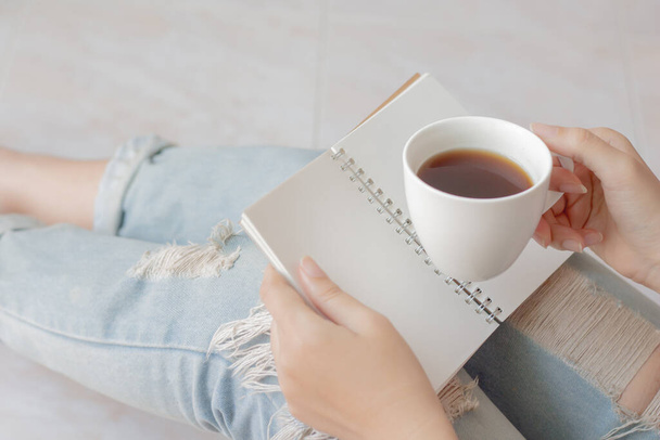 Žena pije kávu a drží zápisník pro psaní deníku. - Fotografie, Obrázek