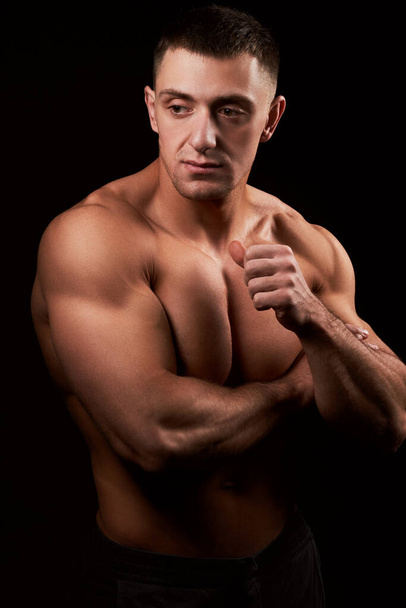 Portrait of muscular bodybuilder on black background.Studio shot - Zdjęcie, obraz
