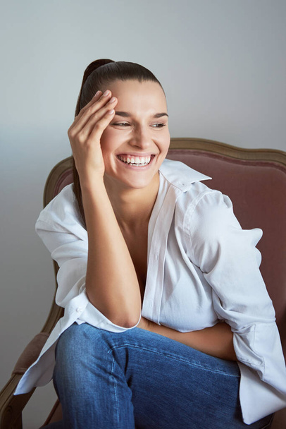 Laughing woman in armchair. Studio shot. - Фото, зображення