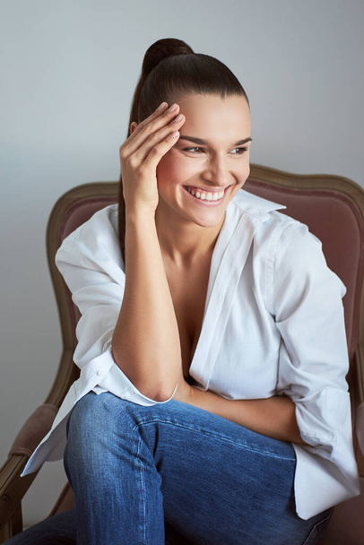 Laughing woman in armchair. Studio shot. - Foto, afbeelding