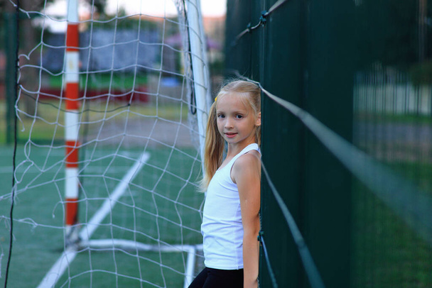 スポーツ場でサッカーのゴール近くにポーズをとる女の子. - 写真・画像
