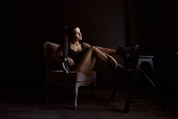 Silhouette of woman's body sitting on sofa in black background - Foto, Bild