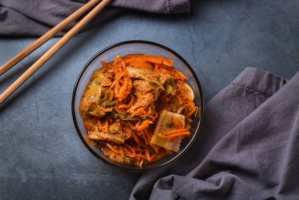 Kotitekoinen orgaaninen perinteinen korealainen kimchi-kaalisalaatti syömäpuikoilla pimeällä pöydällä. Käymisteitse kasvissyöjä, vegaani säilynyt gut terveys ruoka käsite. Tasainen lay, kopioi tilaa tausta. - Valokuva, kuva