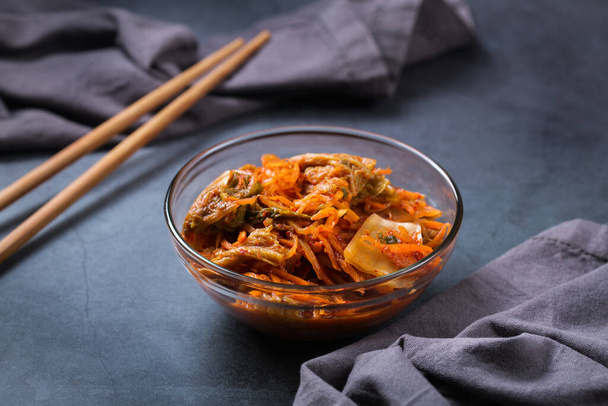 Zelfgemaakte biologische traditionele koreaanse kimchi koolsalade met eetstokjes op een donkere tafel. Gefermenteerd vegetarisch, veganistisch geconserveerd darmgezondheidsconcept - Foto, afbeelding
