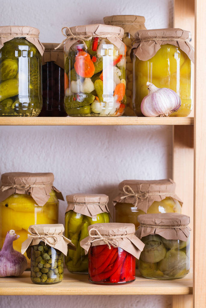 Preserved and fermented food. Assortment of homemade jars with variety of pickled and marinated vegetables on a shelf in the storage room. Housekeeping, home economics, harvest preservation - Photo, Image