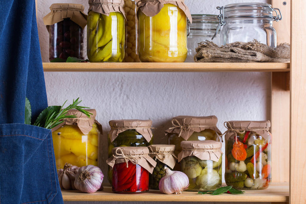 Preserved and fermented food. Assortment of homemade jars with variety of pickled and marinated vegetables on a shelf in the storage room. Housekeeping, home economics, harvest preservation - Fotó, kép
