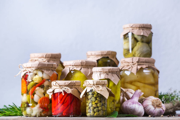 Preserved and fermented food. Assortment of homemade jars with variety of pickled and marinated vegetables on a wooden table. Housekeeping, home economics, harvest preservation   - Photo, Image