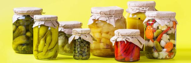 Konservierte und fermentierte Lebensmittel. Auswahl hausgemachter Gläser mit verschiedenen eingelegten und marinierten Gemüsesorten auf einem Tisch. Hauswirtschaft, Hauswirtschaft, Ernteerhaltung. Banner - Foto, Bild