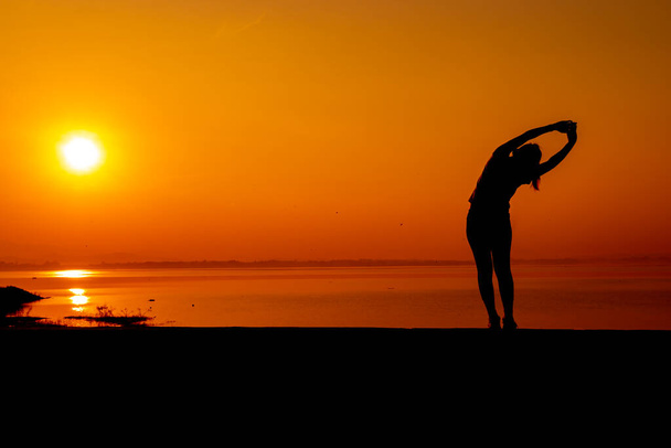 Sylwetka kobieta trening sam z zachodem słońca tle. Zdrowe i samodzielne ćwiczenia. Styl życia wellness i rekreacja na świeżym powietrzu. - Zdjęcie, obraz