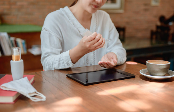 Mulher de negócios asiática limpando a mão e o computador antes de acordar online. Distanciamento social e novo estilo de vida normal. - Foto, Imagem