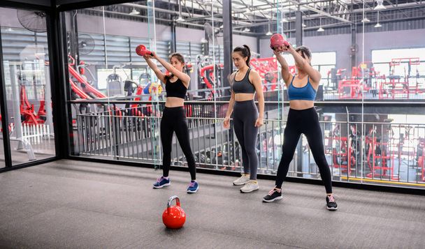 Asiatische Frauen bewegen sich und leben im Fitnessstudio. Sportliches Frauentraining mit Trainer und Kurzhantelgewicht. Wellness und gesund fürs Bodybuilding. - Foto, Bild